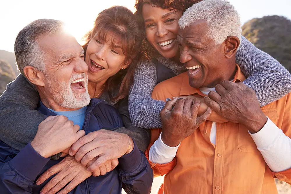 Smiling Senior Friends Having Fun Walking In Countryside Together