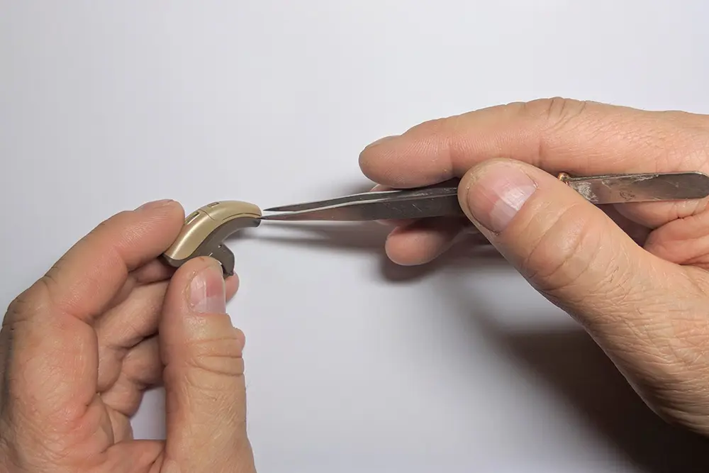 Closeup of two hands repairing a hearing aid