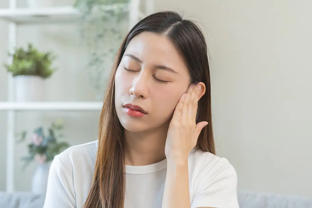 woman holding her ear