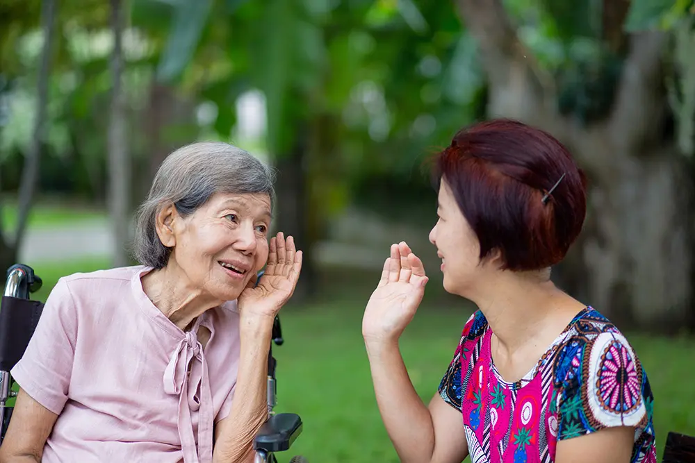 Hard of hearing woman trying to talk with daughter in the park.