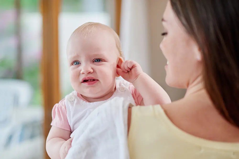 mother holding baby with an ear infection