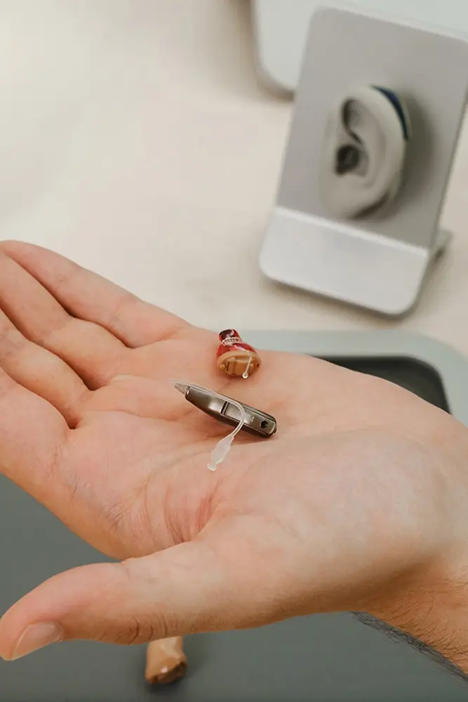 closeup of hand holding miniature hearing aids